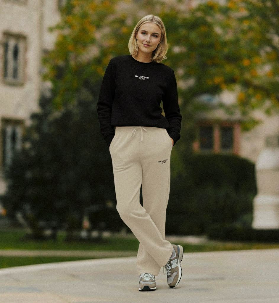 Woman wearing a black sweatshirt and beige pants standing outdoors with blurred background