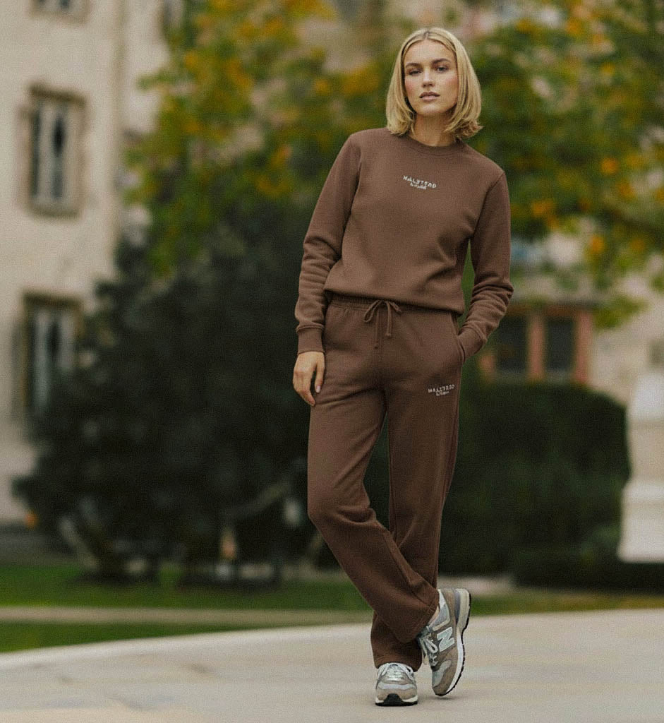 Woman wearing a brown outfit with 'Rafale' branding in an outdoor setting.