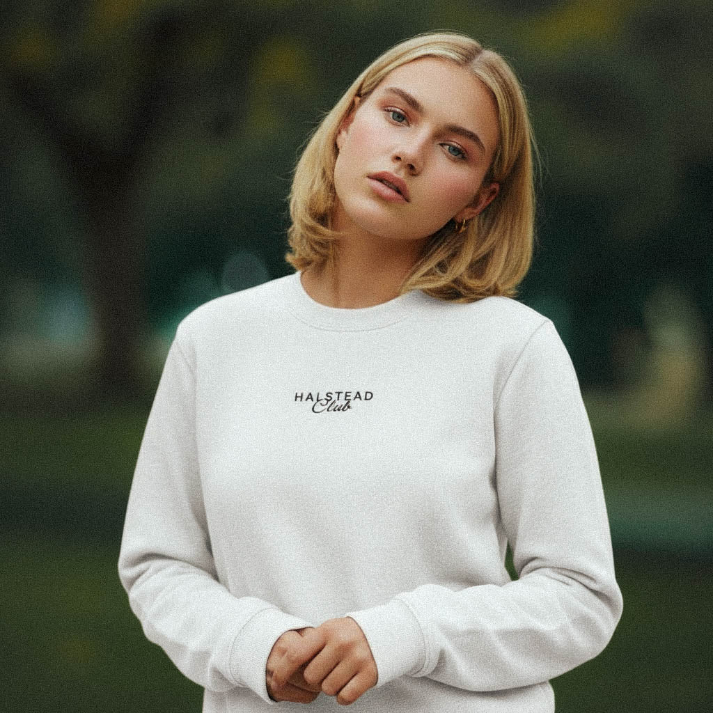 Woman wearing a white sweatshirt with 'Halstead Club' text in an outdoor setting