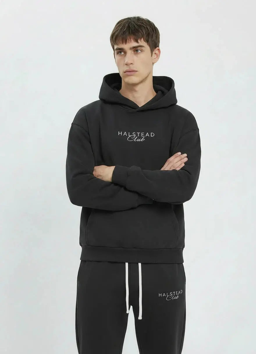 Man wearing a black hoodie and pants with 'Halstead Club' branding on a white background