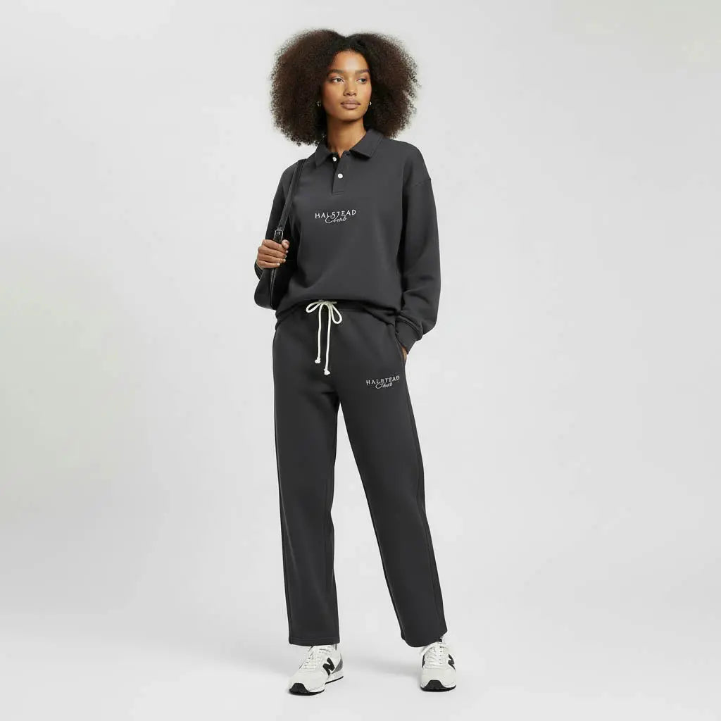Person wearing a black tracksuit with brand logo on a white background