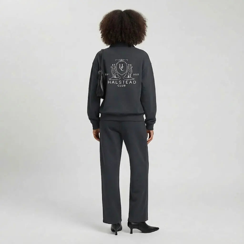 Person wearing a dark gray tracksuit with 'Halstead Club' logo on a light gray background