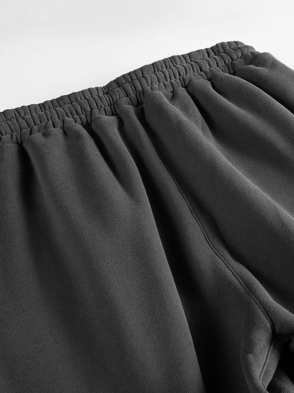Close-up of dark gray pants with an elastic waistband on a light gray background