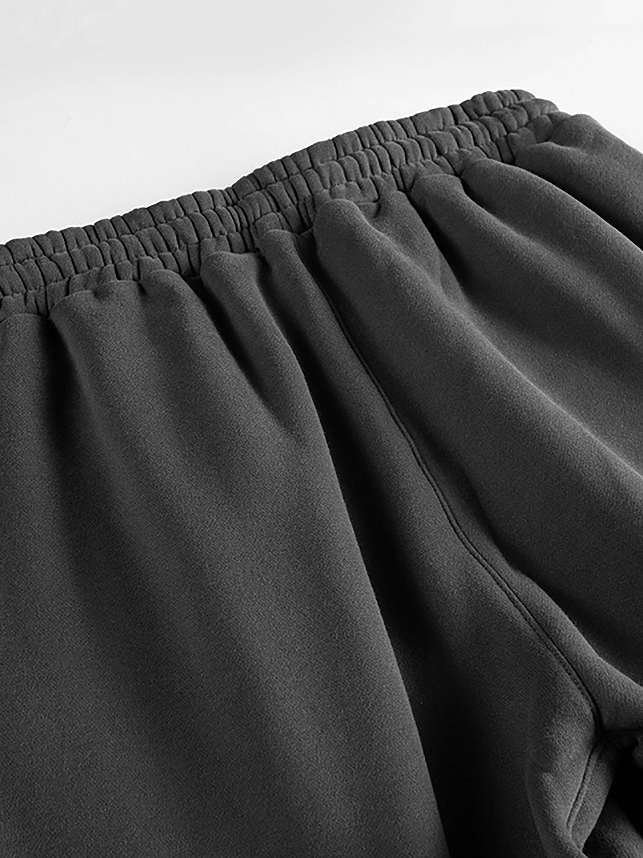 Close-up of dark gray pants with an elastic waistband on a light gray background