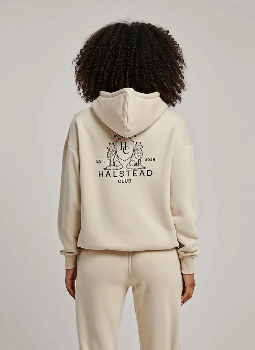 Person wearing a beige hoodie with 'Halstead Club' logo on the back, standing against a plain background