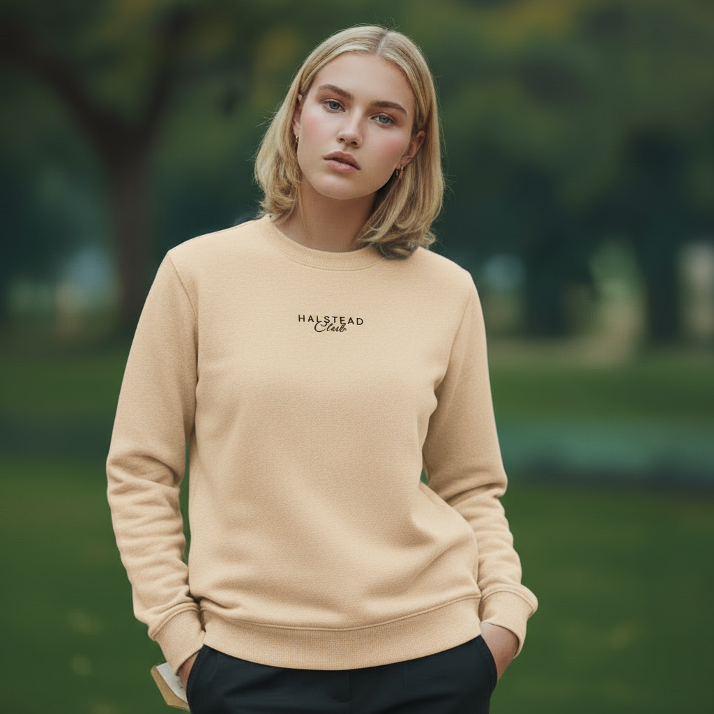 Woman wearing a beige sweatshirt with 'HARSTED' logo in a park setting
