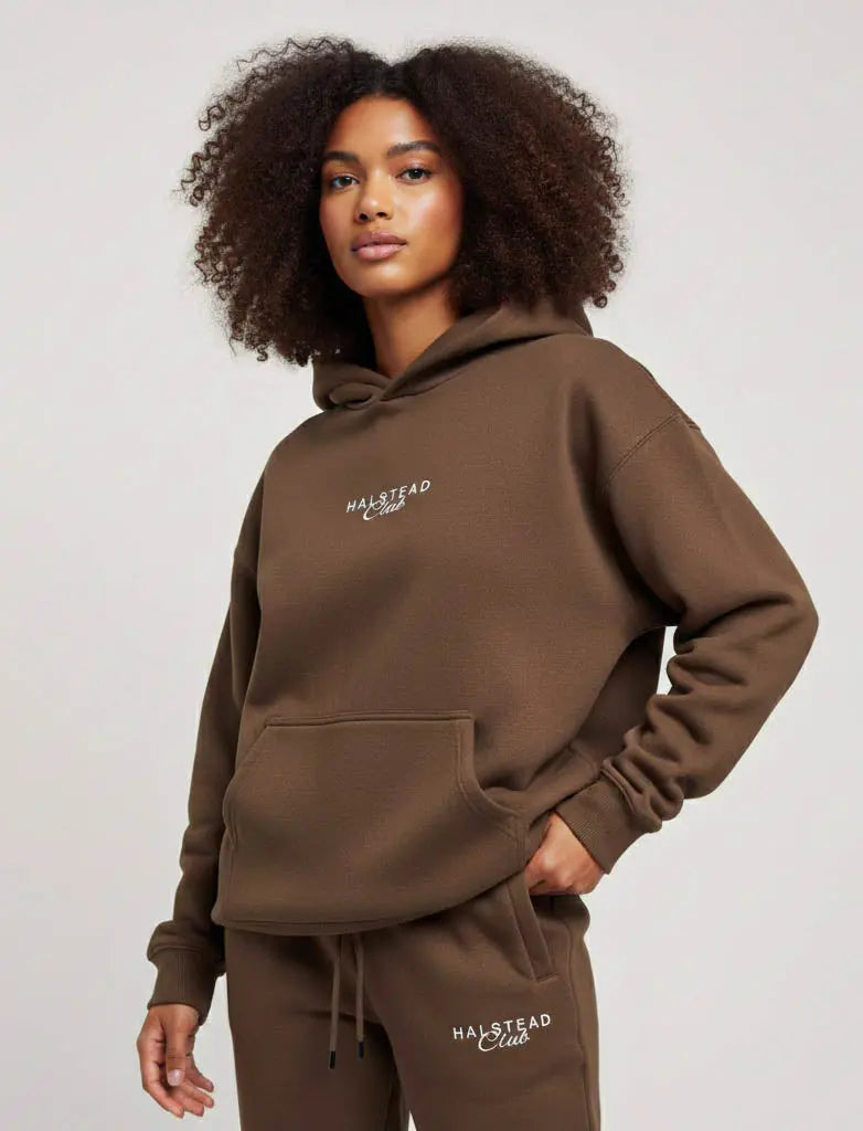 Woman wearing a brown hoodie and pants with 'Malstead' branding on a plain background