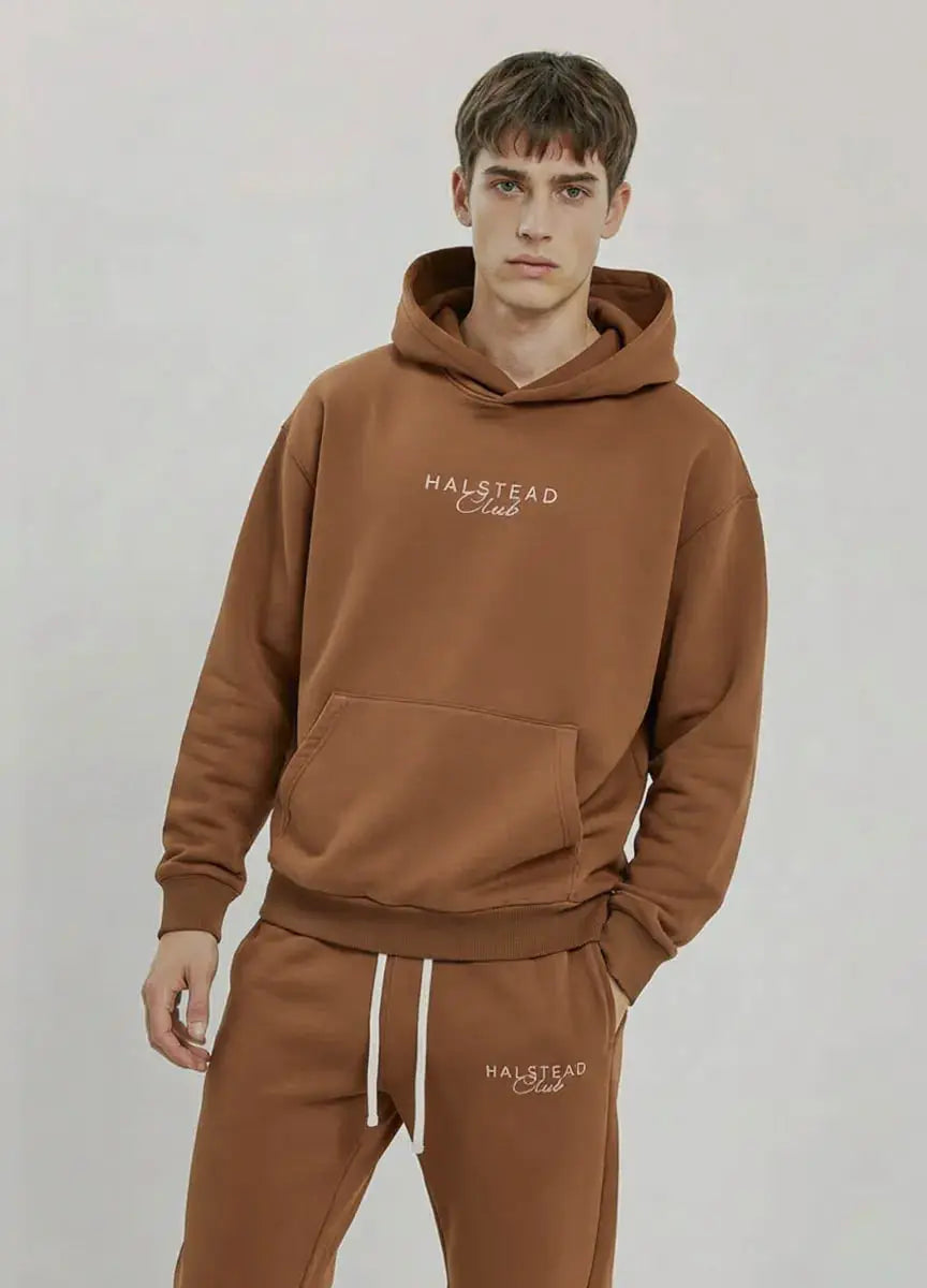Man wearing a brown hoodie and pants with 'Halstead Club' branding on a light gray background