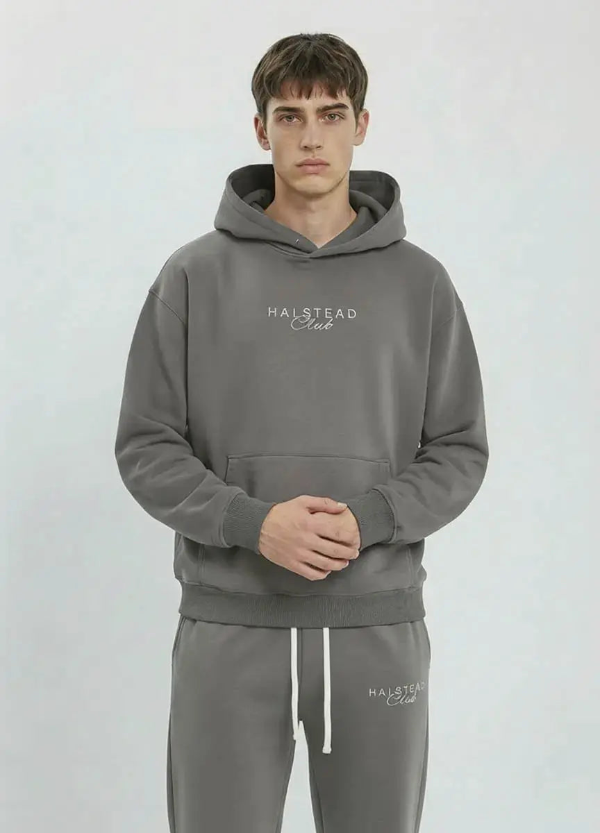 Man wearing a gray hoodie and pants with 'Halstead Club' branding on a light gray background