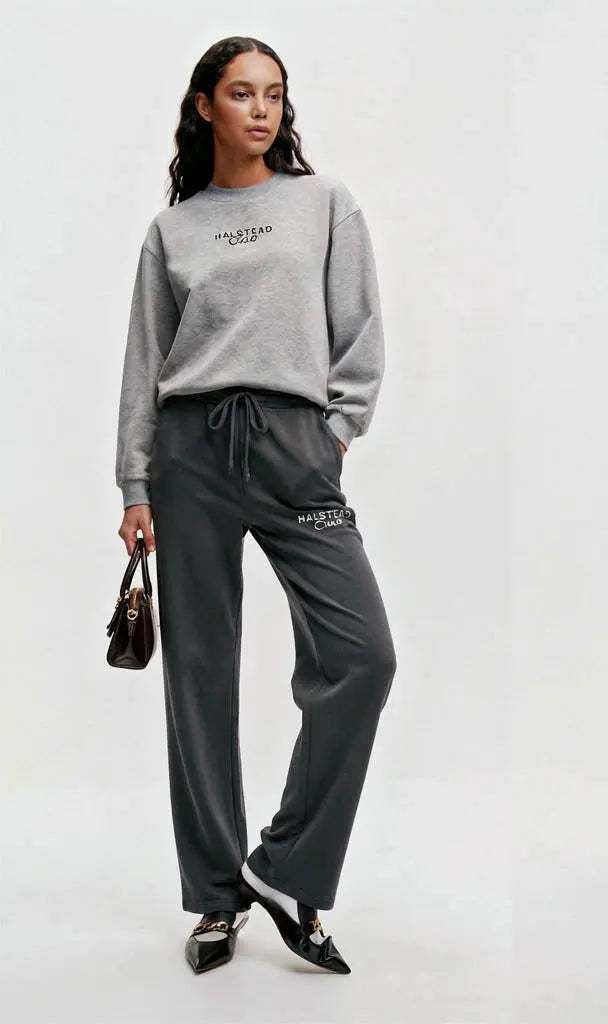 Woman wearing a gray sweatshirt and pants with 'Valentino' branding on a white background