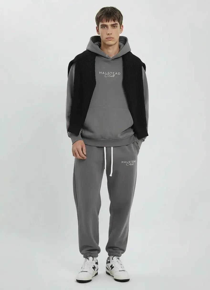 Person wearing a gray tracksuit with a black vest on a white background