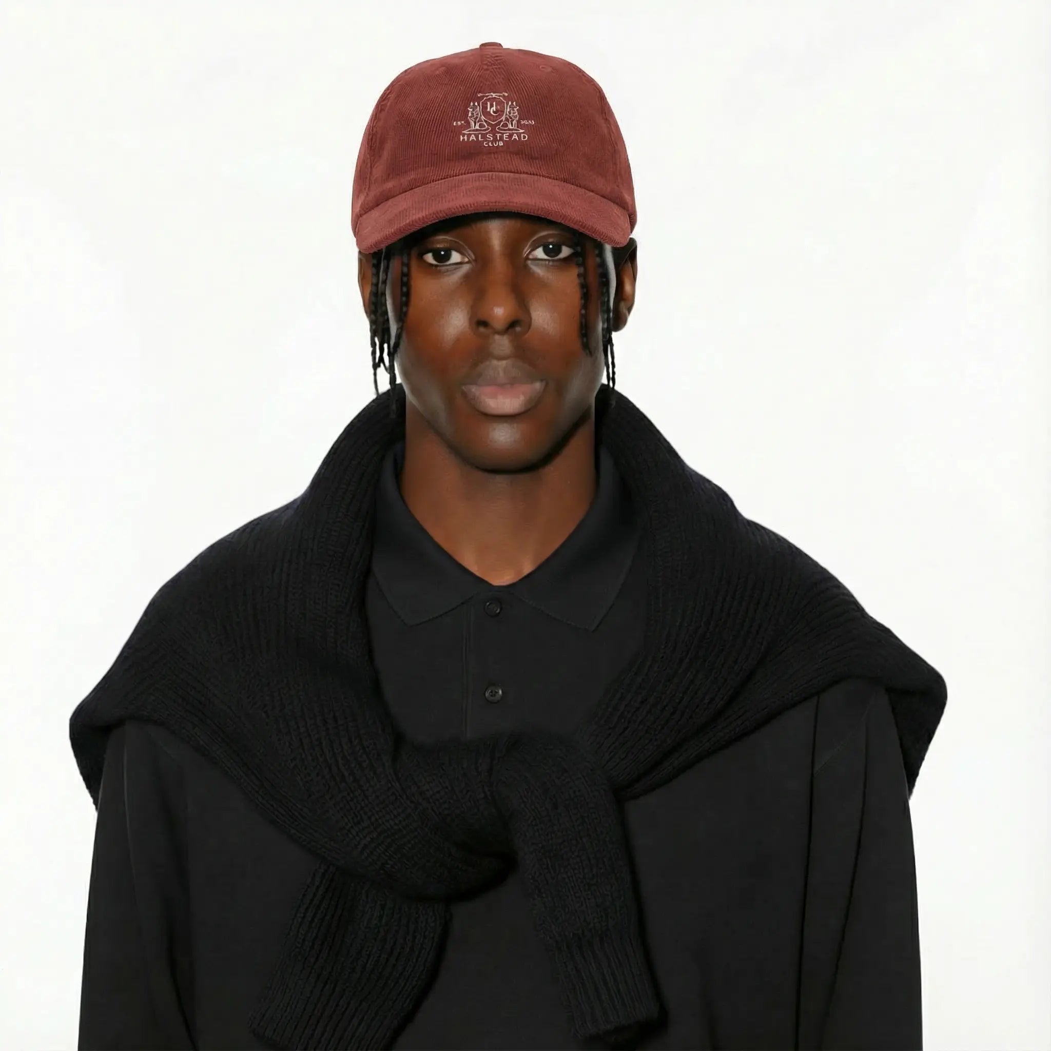 Person wearing a maroon cap and black sweater on a white background