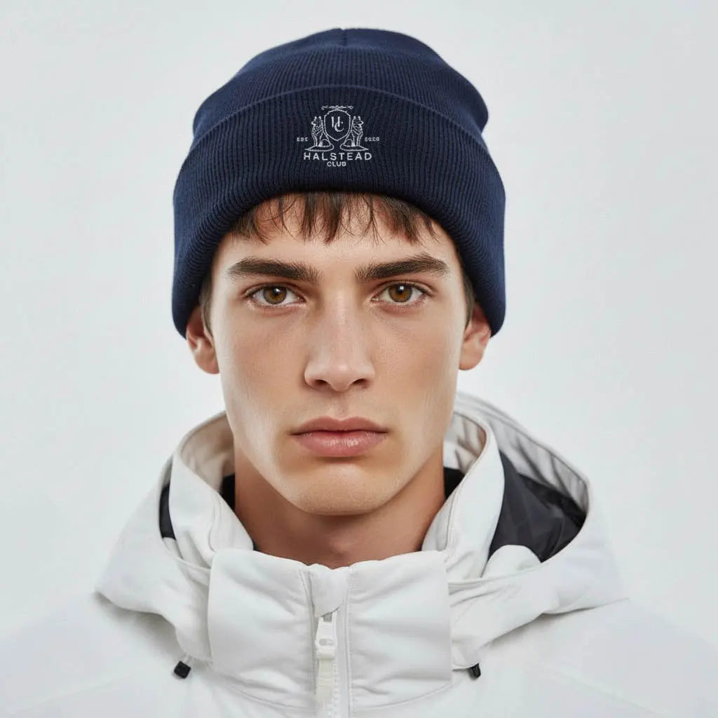Person wearing a navy beanie with a logo on a light gray background