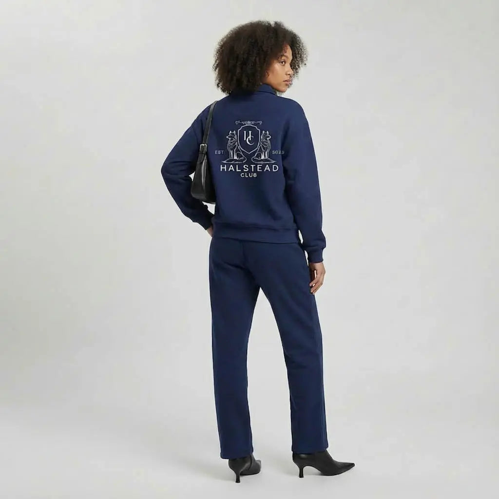 Person wearing a navy tracksuit with 'Halstead Club' logo on a white background