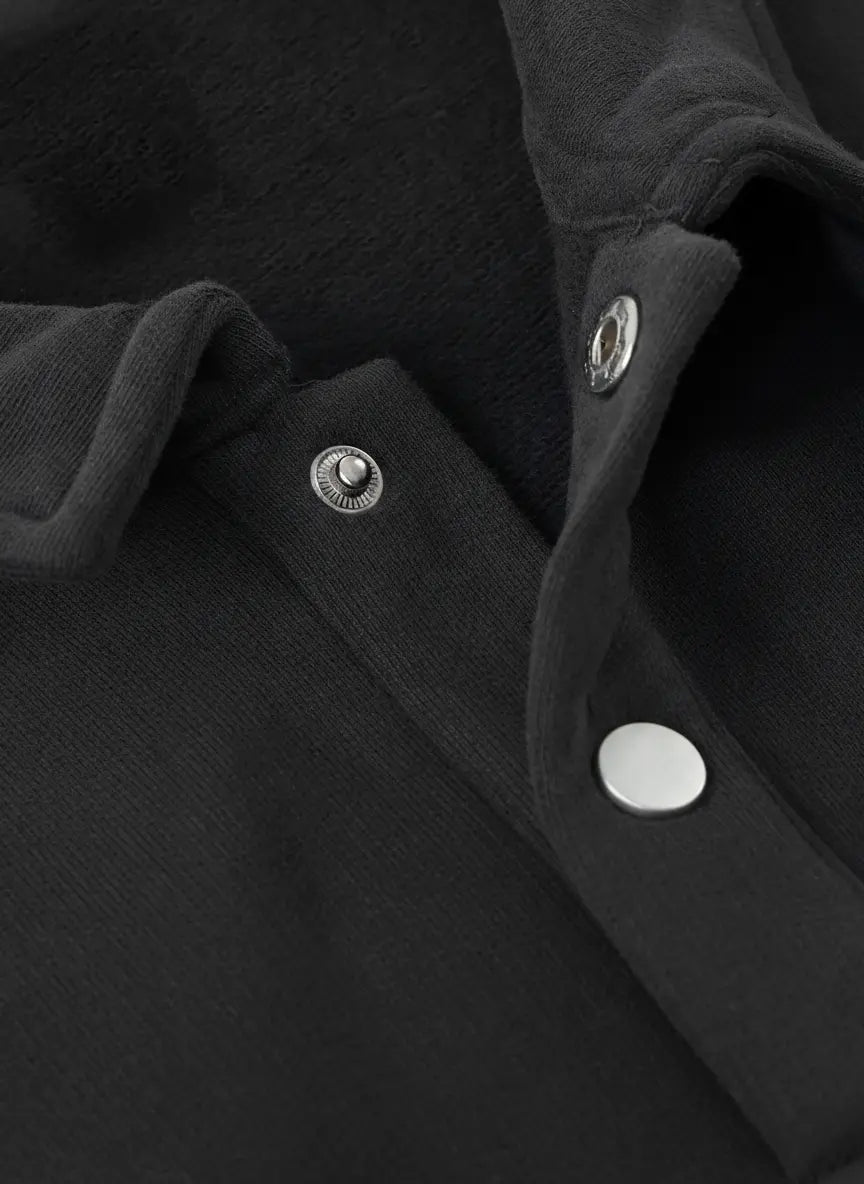 Close-up of a black garment with silver buttons