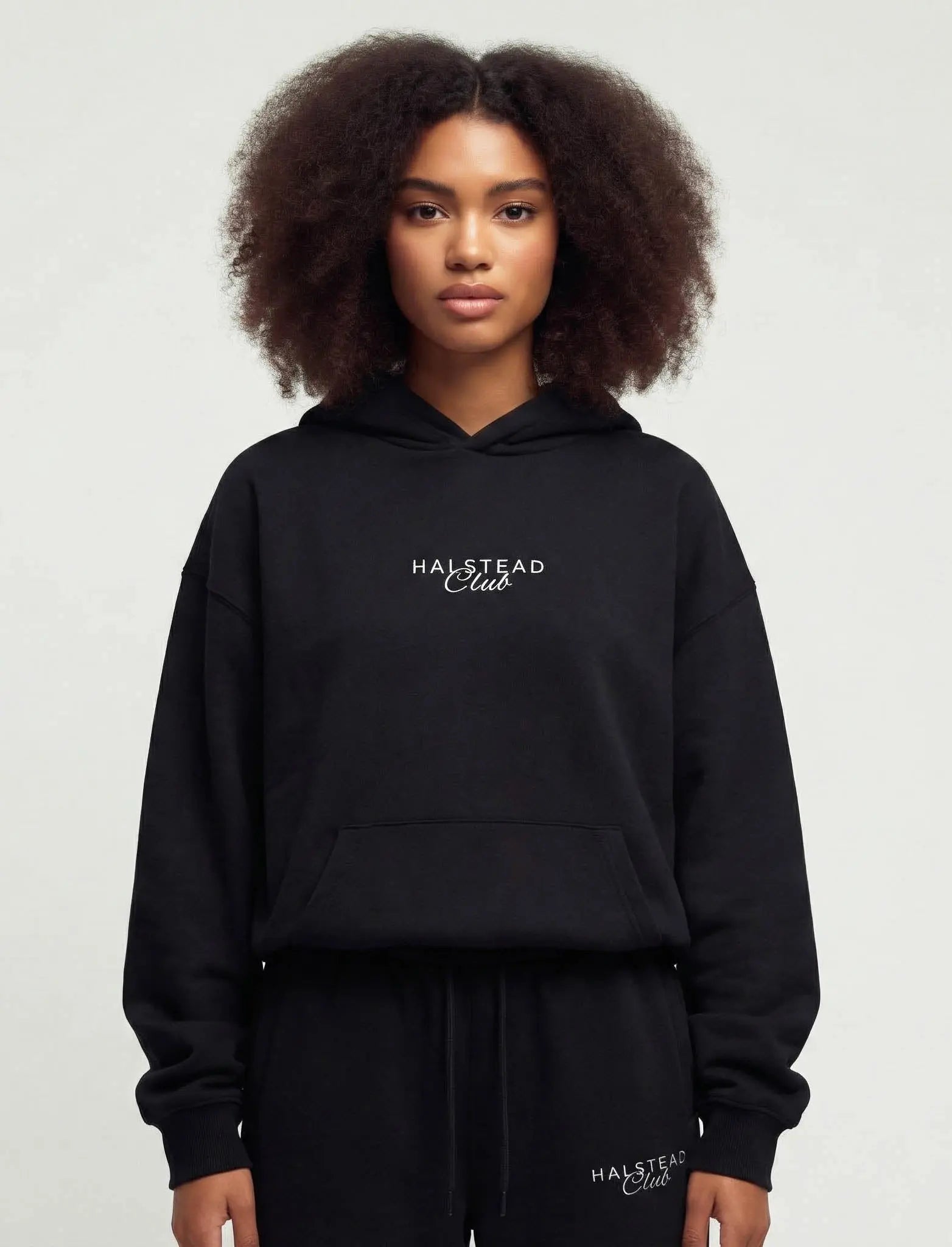 Person wearing a black hoodie with 'Halstead Club' embroidery on a plain background