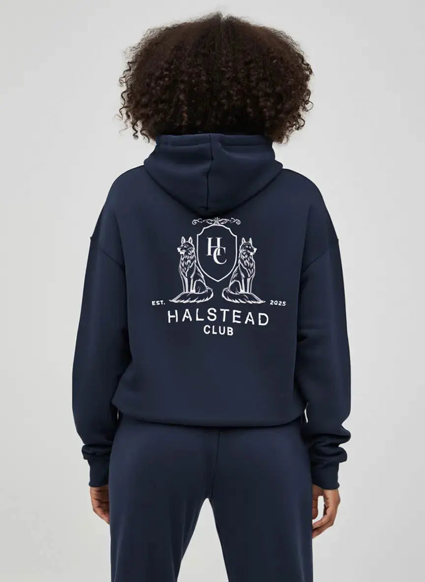 Person wearing a navy hoodie with 'Halstead Club' logo on the back against a white background