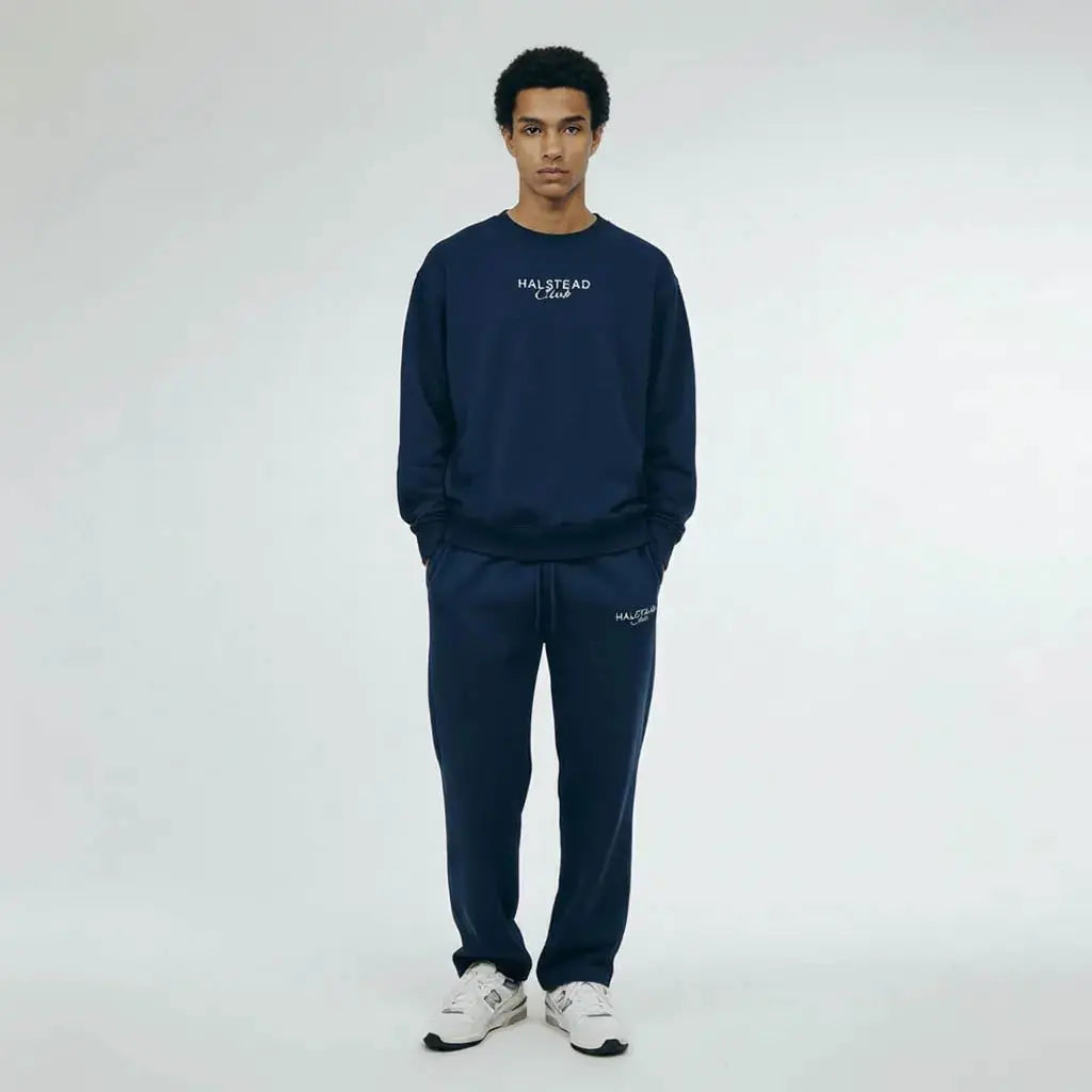 Person wearing a navy tracksuit with 'Halstead Club' branding on a white background