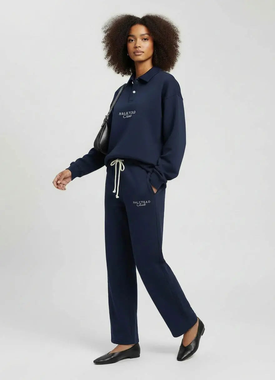 Woman wearing navy tracksuit with visible branding on a white background